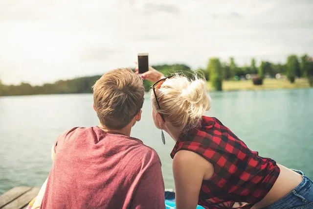 水辺でSnapchat用の自撮りをするカップル