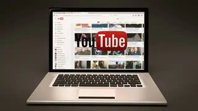Schermo del laptop con miniature di video di YouTube sovrapposte a un logo di YouTube