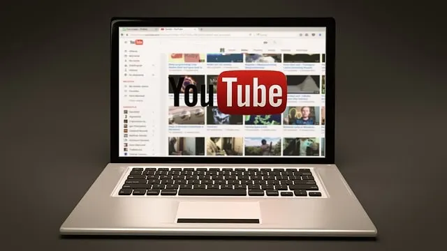 Laptop-Bildschirm mit YouTube-Video-Miniaturansichten, überlagert von einem YouTube-Logo