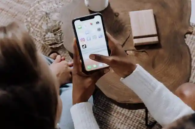 Two people holding phone and clicking TikTok icon