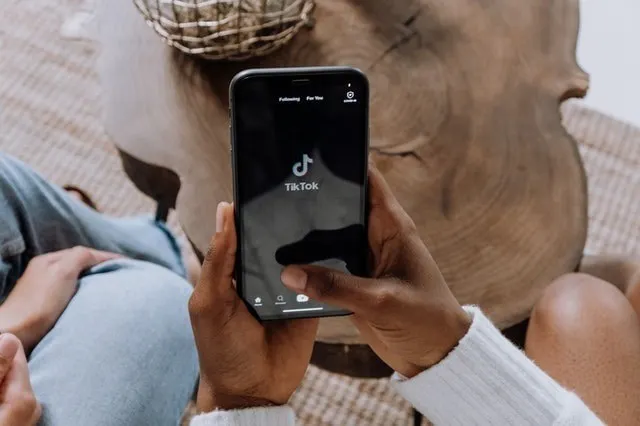 Manos de una persona sosteniendo un smartphone con pantalla de TikTok