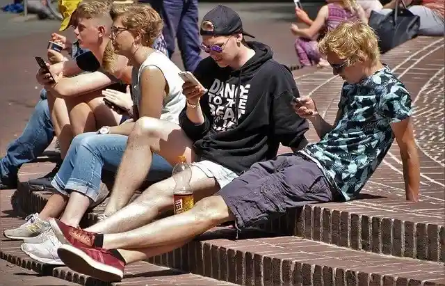 Teens sitting on steps outside using mobile devices