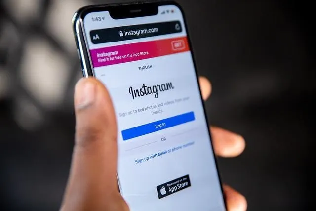 Instagramのログイン画面が表示されたモバイルデバイスを持つ手