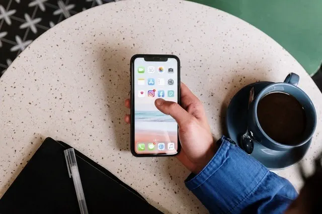 Téléphone affichant une notification Instagram à côté d'un café et d'un carnet de notes.