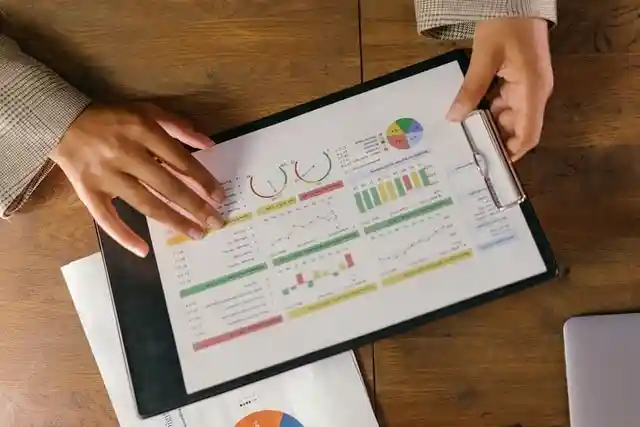 Persona sosteniendo un portapapeles con datos de análisis de marketing en tablas y gráficos