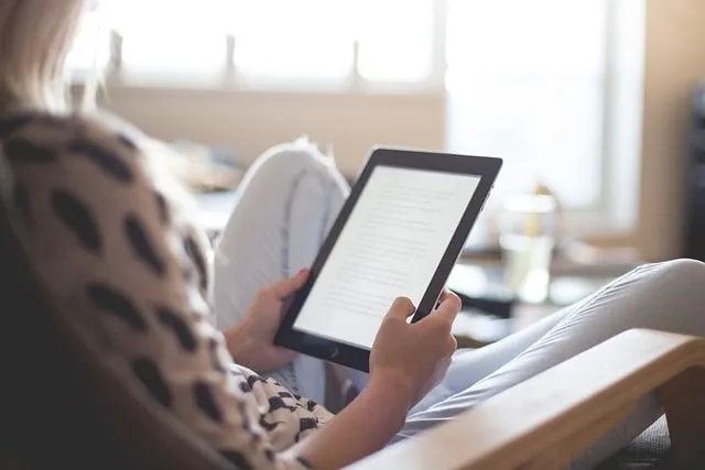 Mujer leyendo un libro electrónico en un ereader o Amazon Kindle