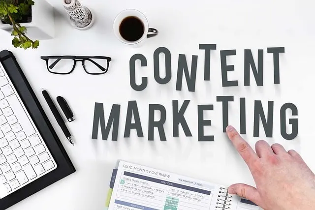 Main désignant les mots "content marketing" sur une table avec un cahier et un clavier.